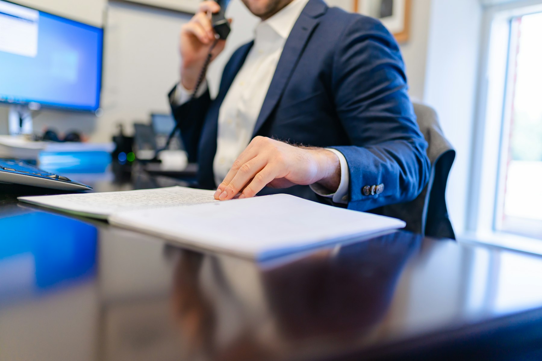 A lawyer in a suit on the phone, hand resting on handwritten case notes